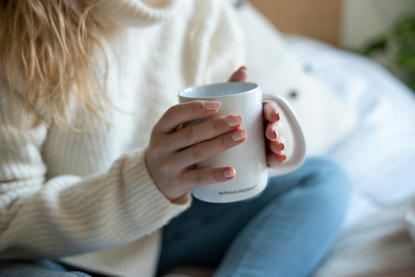 a woman sitting on a bed holding a coffee mug